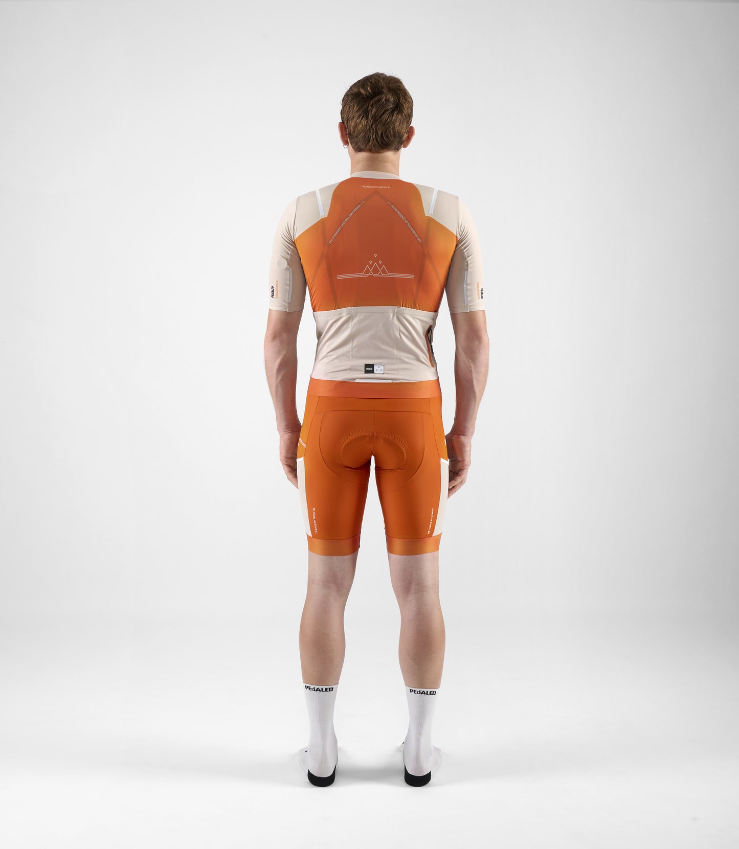 23SBBTC12PE_6_men cycling bib shorts transcontinental orange total body back pedaled