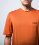 23STSJA0HPE_5_cycling gravel tech tee orange jary front logo pedaled