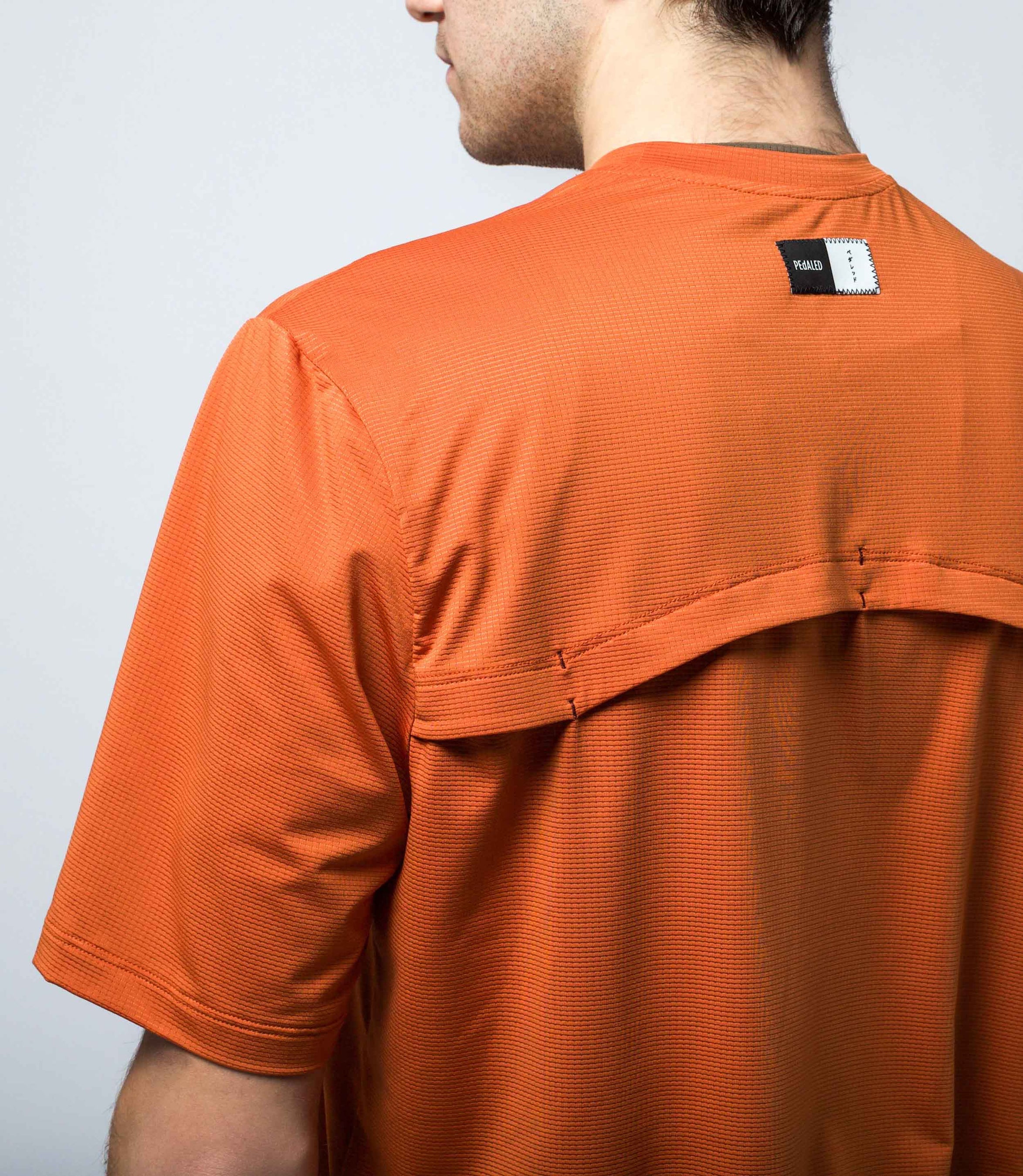 23STSJA0HPE_8_gravel tech tee cycling orange jary back logo pedaled