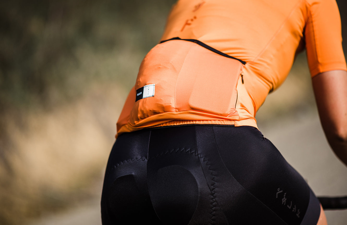 W1SJSMI12PE_8_women cycling jersey back pocket orange mirai pedaled